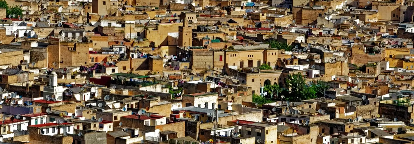 El viaje de tres días desde Fez al desierto comienza con una densa vista aérea de la antigua Medina de Fez, que muestra un mar de edificios tradicionales con antenas parabólicas.
